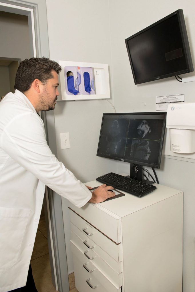 Dr. Blanco assessing the CBCT digital scan at a computer monitor while standing