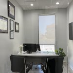 Consultation office in Magnolia Dental with a desk, chairs, and framed certificates on the wall.