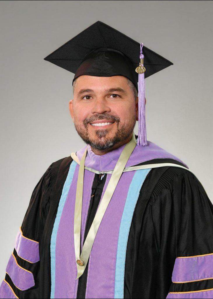 Dr. Yosvel Blanco Sanchez wearing a graduation gown and cap