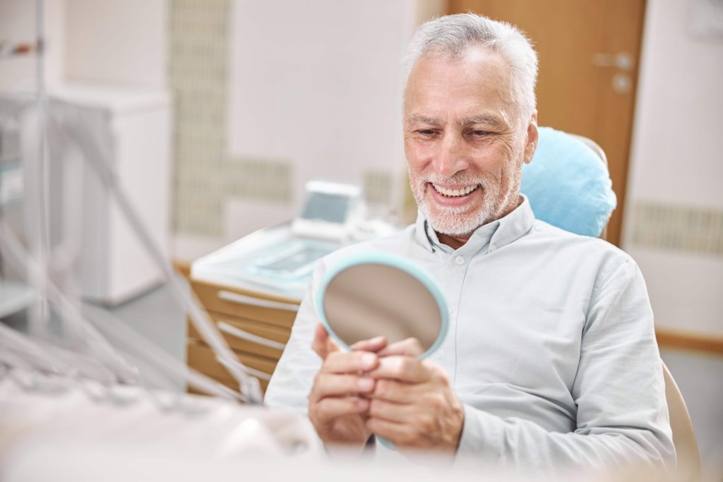 a man looking in the mirror at his new full arch dental implants